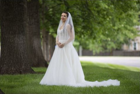 Bride standing outdoors beneath a large tree