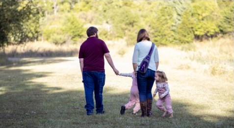 Family walking together through a sunlit outdoor path