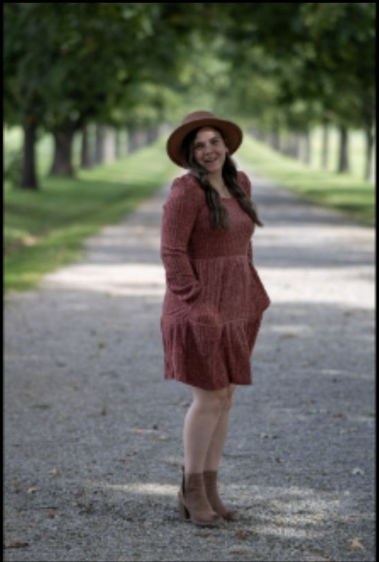 Outdoor portrait in orange dress on a tree-lined path