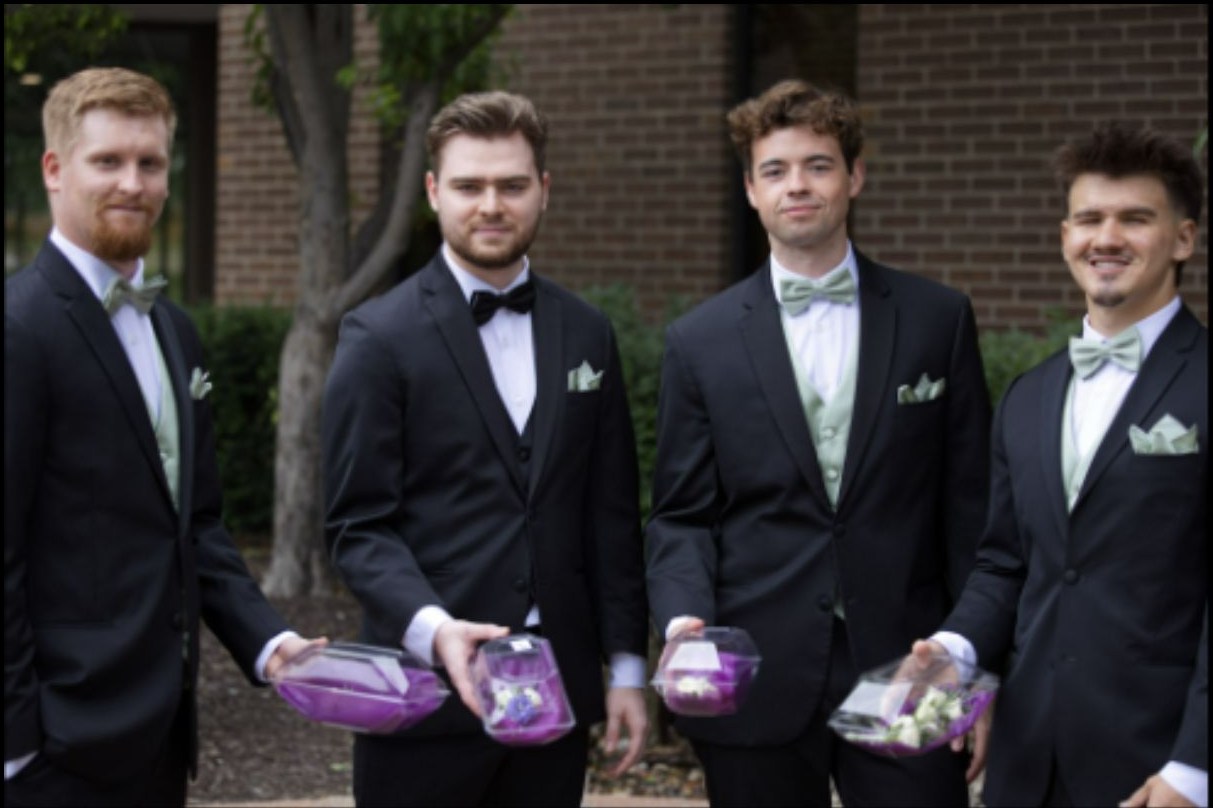 Groomsmen holding purple floral details outdoors