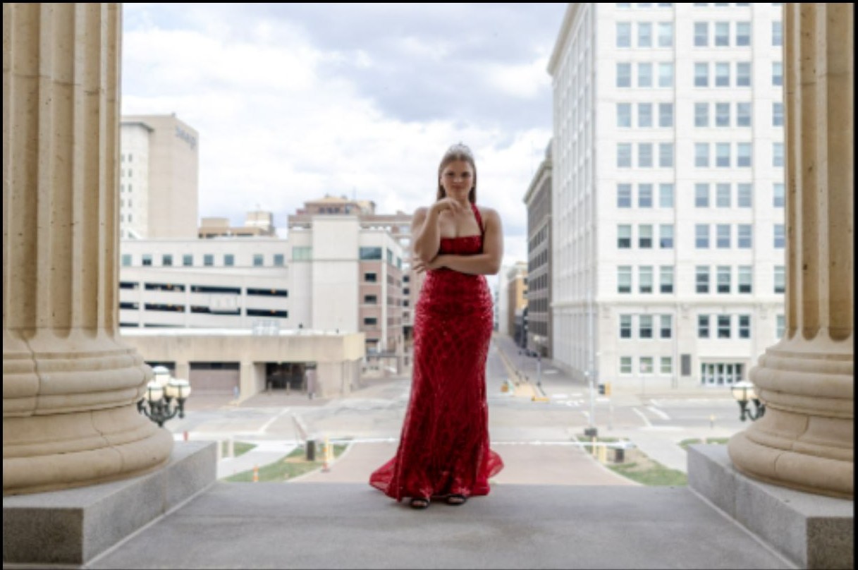 Editorial senior portrait in a red dress with city architecture