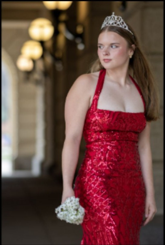 Formal portrait in a red dress beneath glowing interior lights